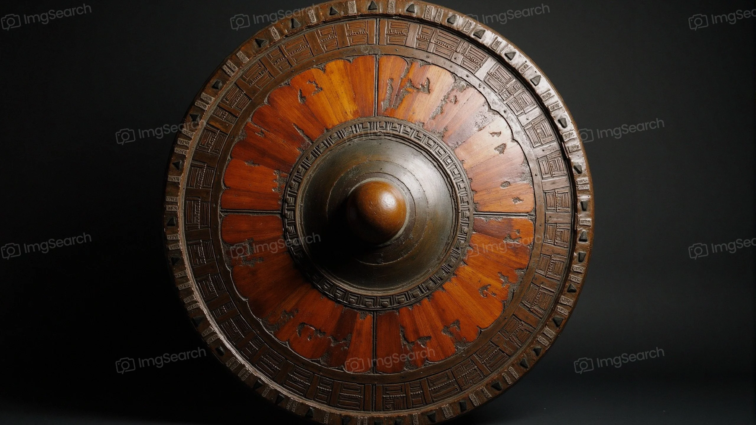 A close-up of an ornate ancient warrior shield showcasing intricate designs a central boss.