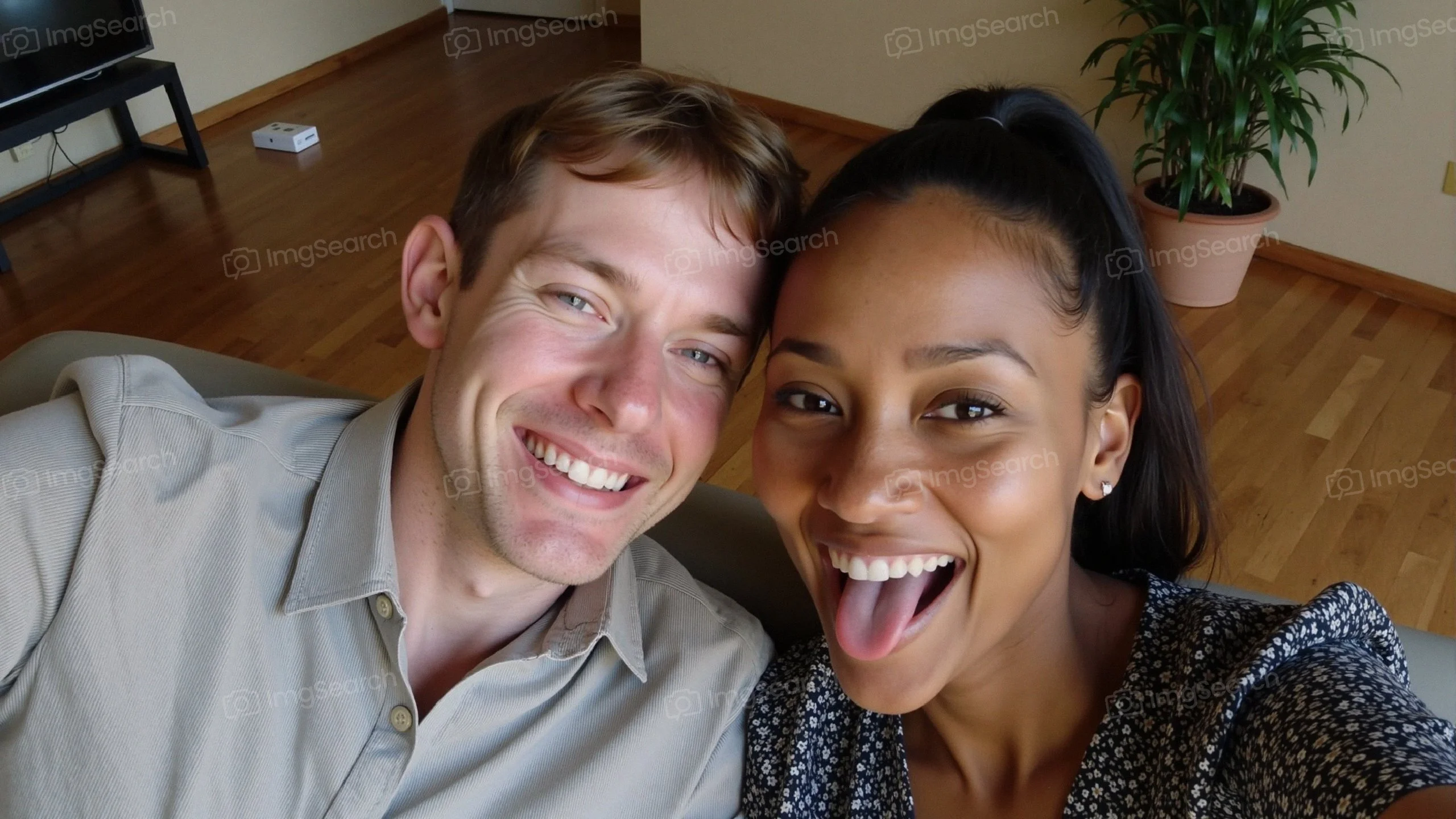 A cheerful couple taking a playful selfie with smiles a tongue out expression.