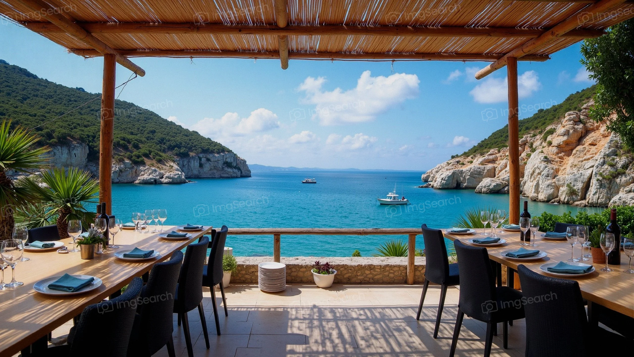 Outdoor dining setup overlooking a sea with boats hills in the background