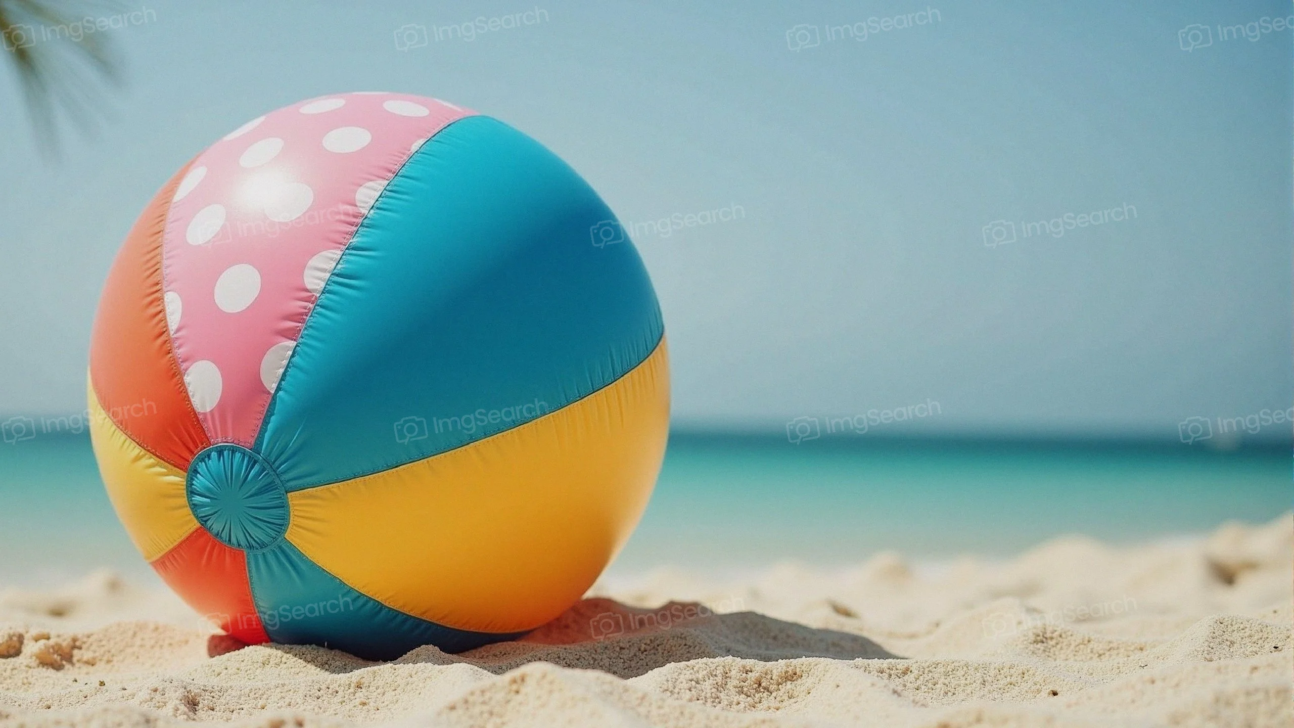 Colorful beach ball lying on the sand with ocean background