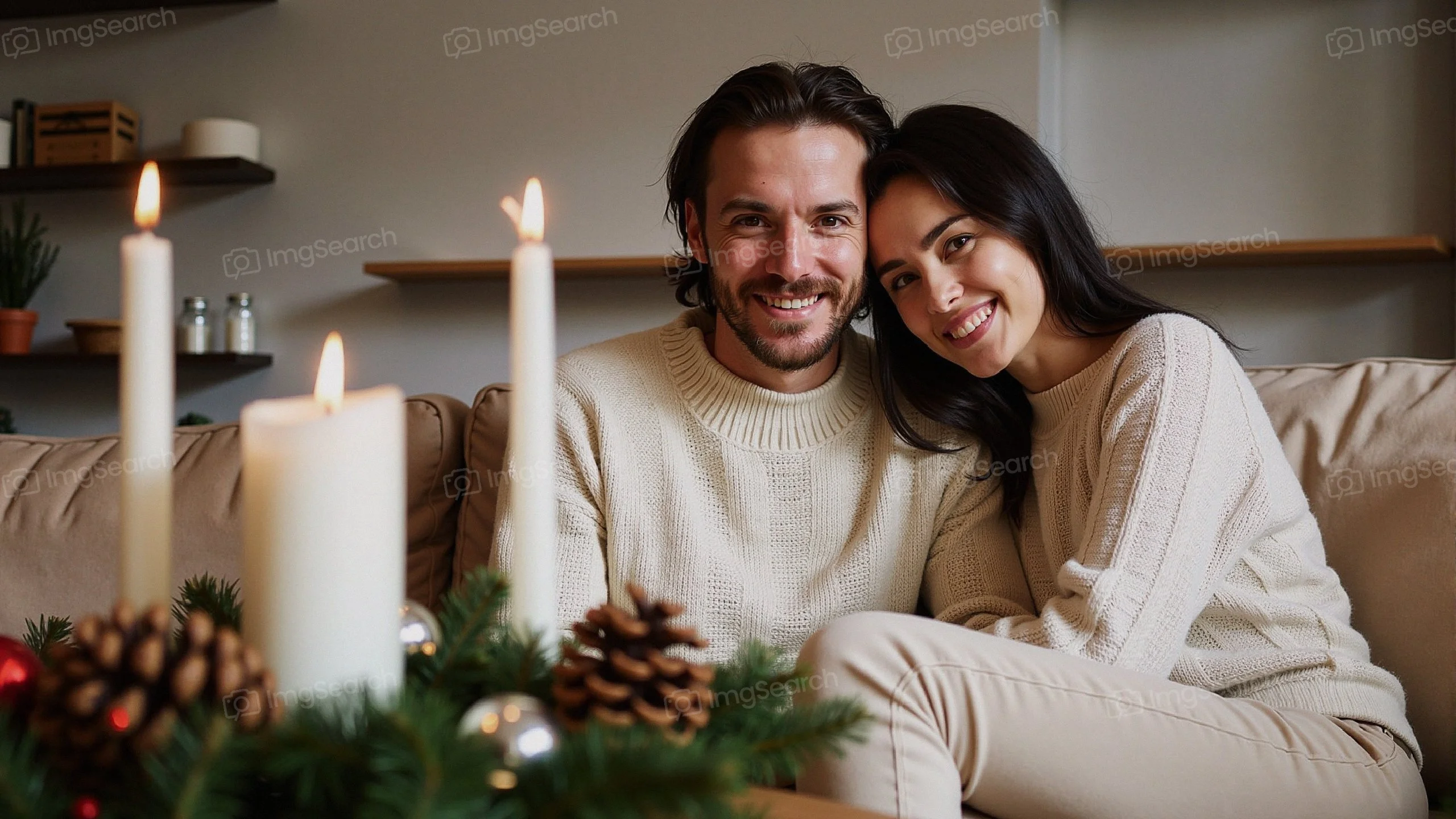 A happy couple sitting together on a sofa, surrounded by candles pine cones, embodying the cozy spirit of winter.