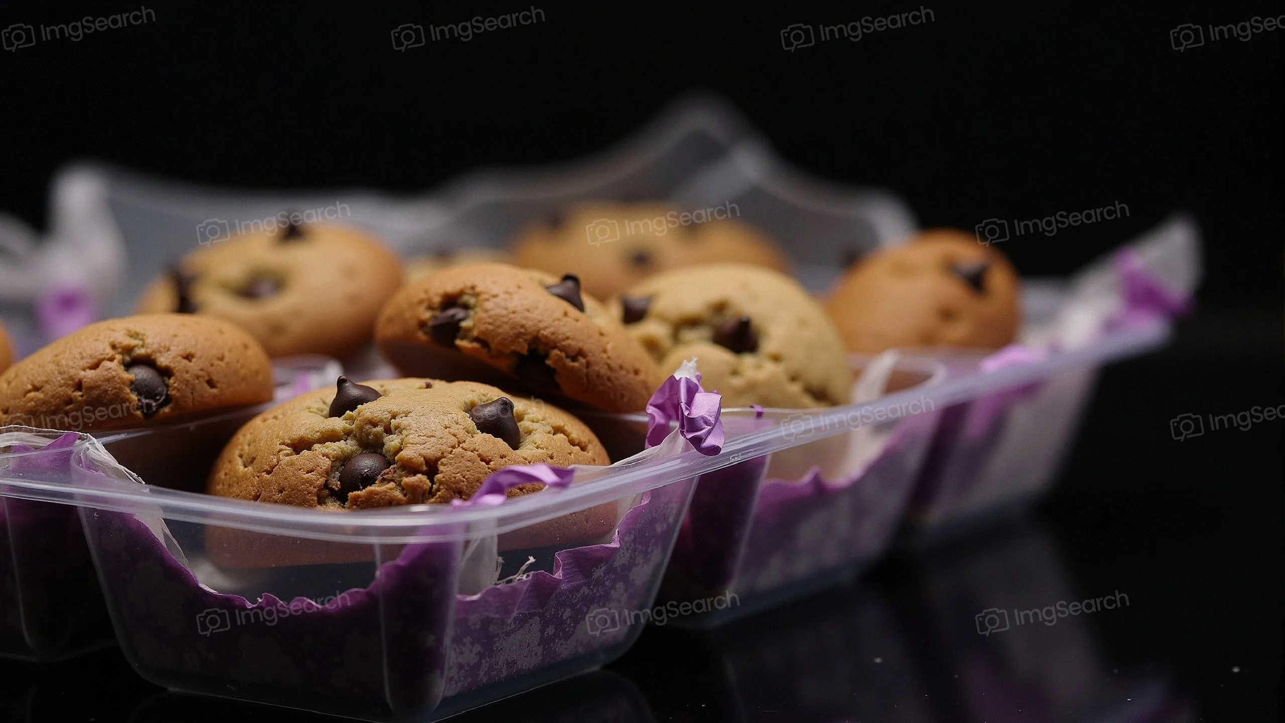 A tray of freshly baked chocolate chip cookies with decorative purple liners.
