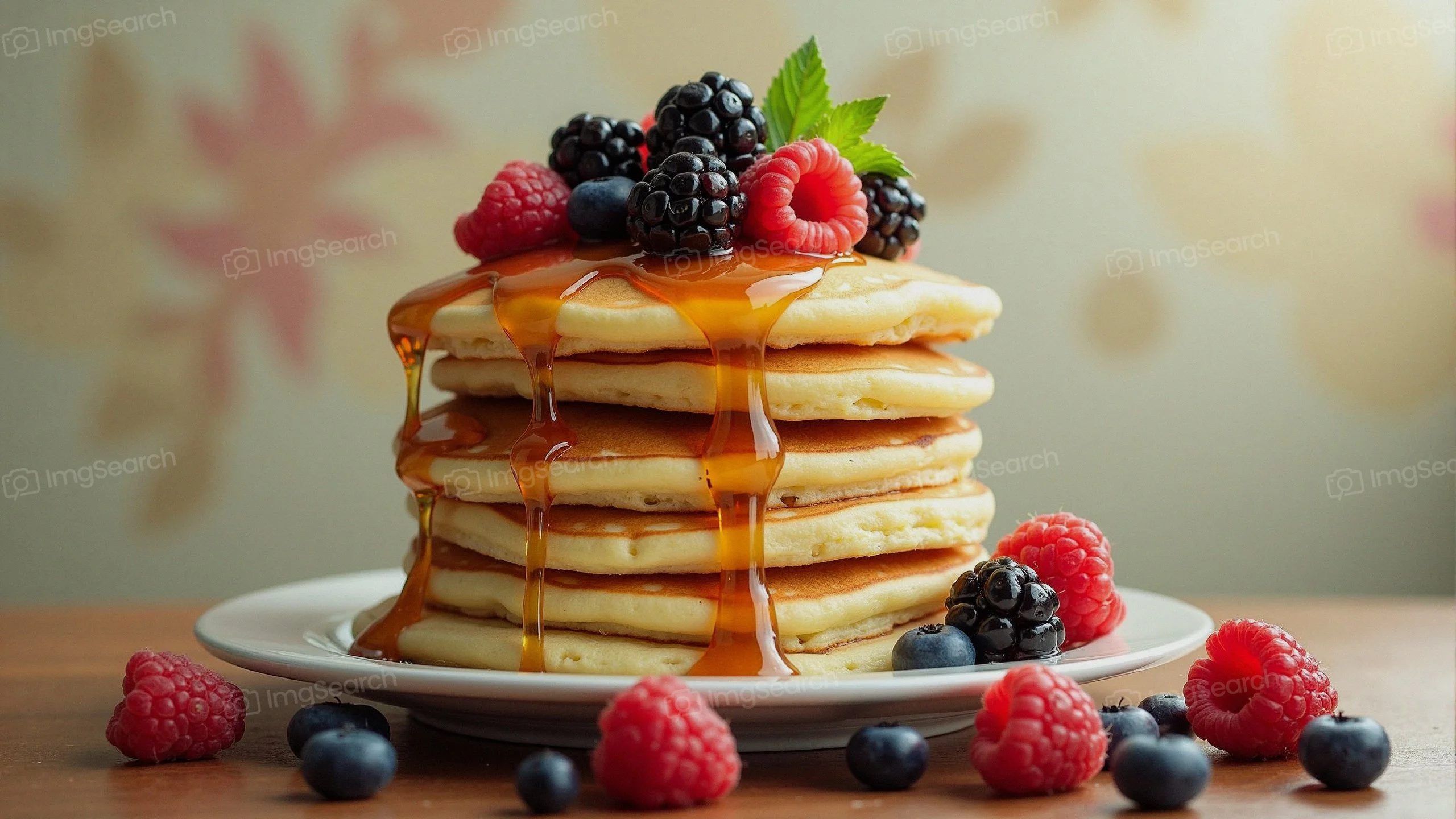 Stack of fluffy pancakes topped with syrup fresh berries on a plate