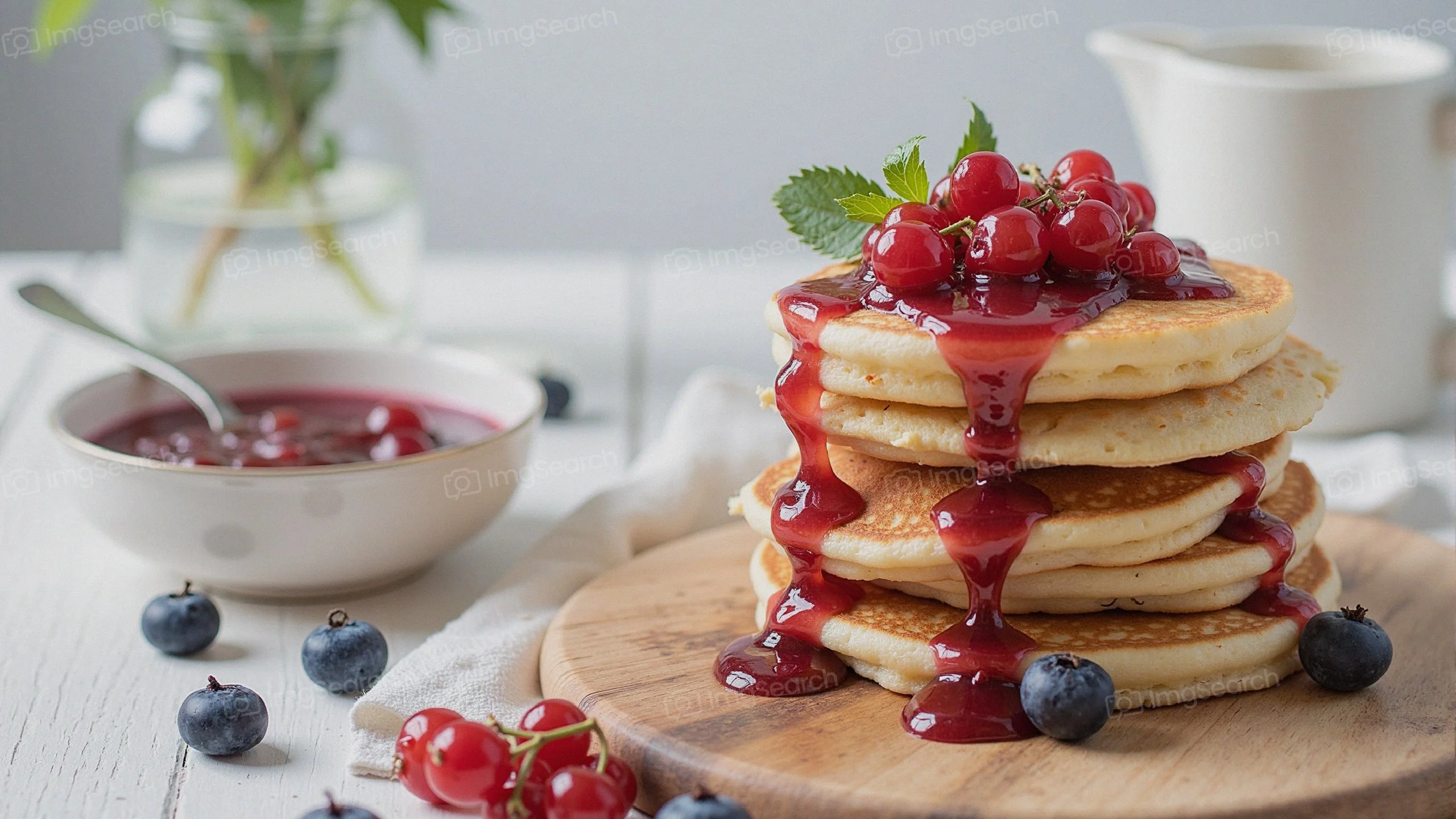 Stack of pancakes topped with berry compote fresh fruits