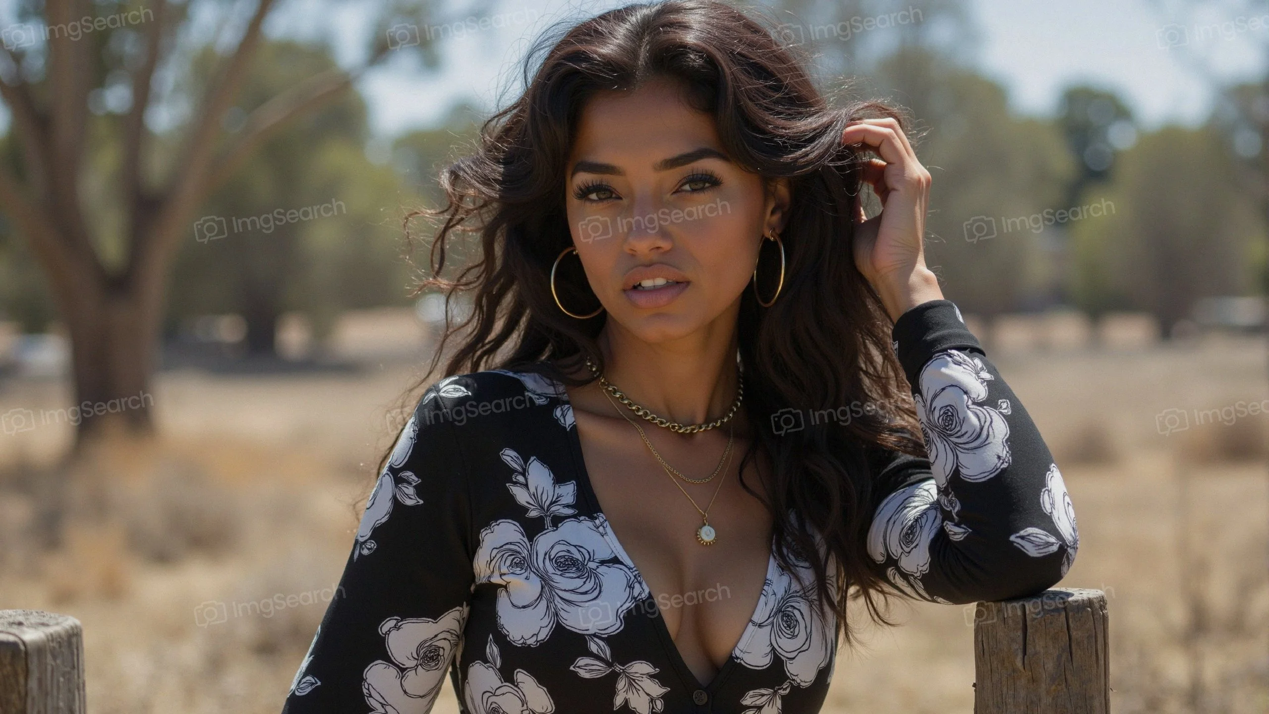 A young woman with long dark hair wearing a floral black dress, posing outdoors.