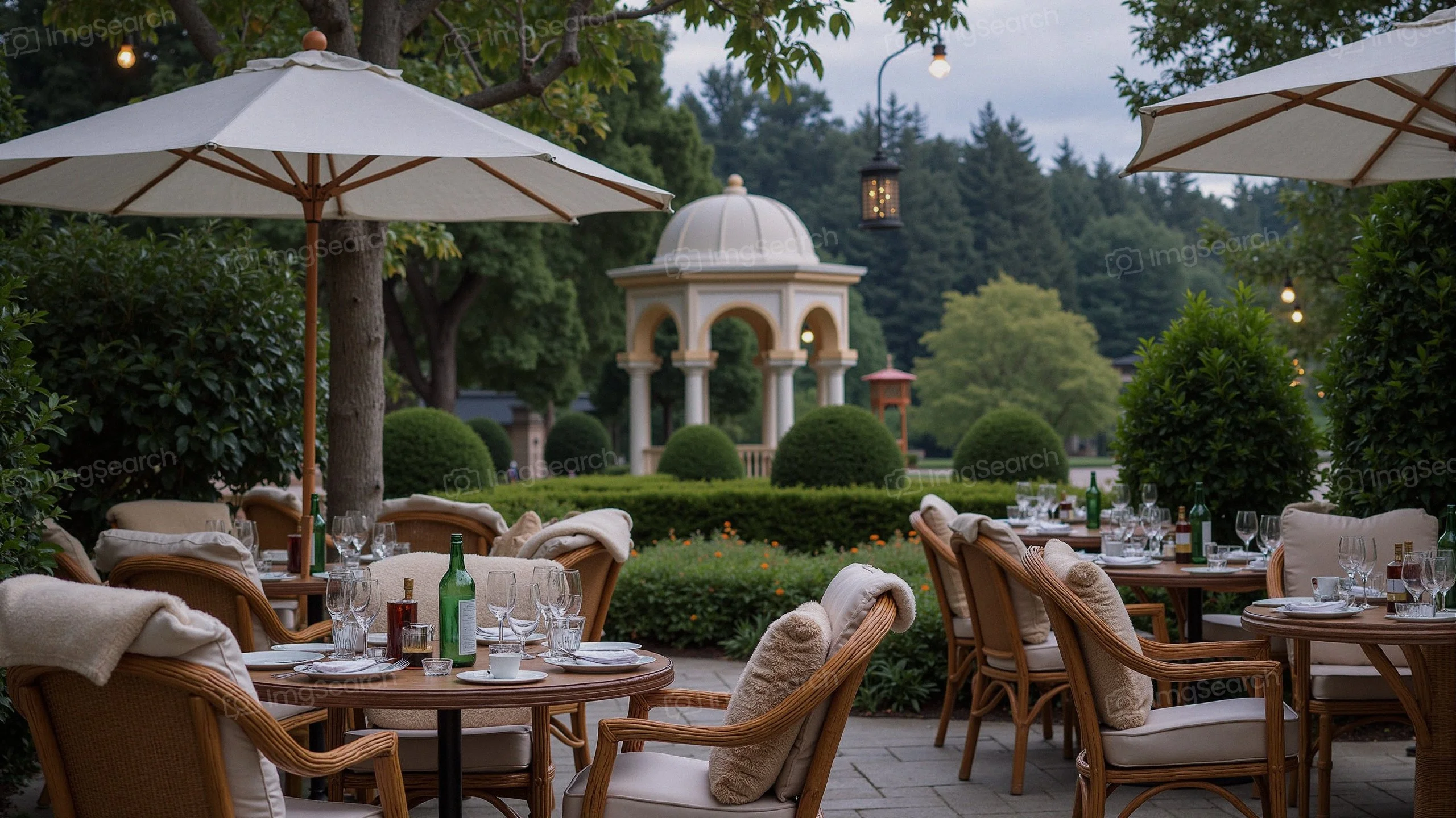 Outdoor dining area with wicker chairs umbrellas in a garden setting featuring a gazebo