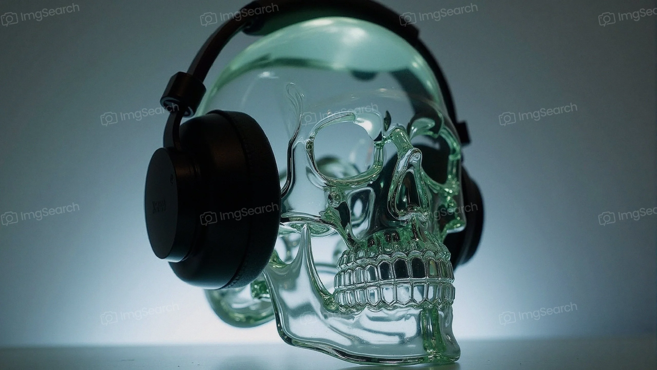 A transparent glass skull wearing black headphones, illuminated from behind.