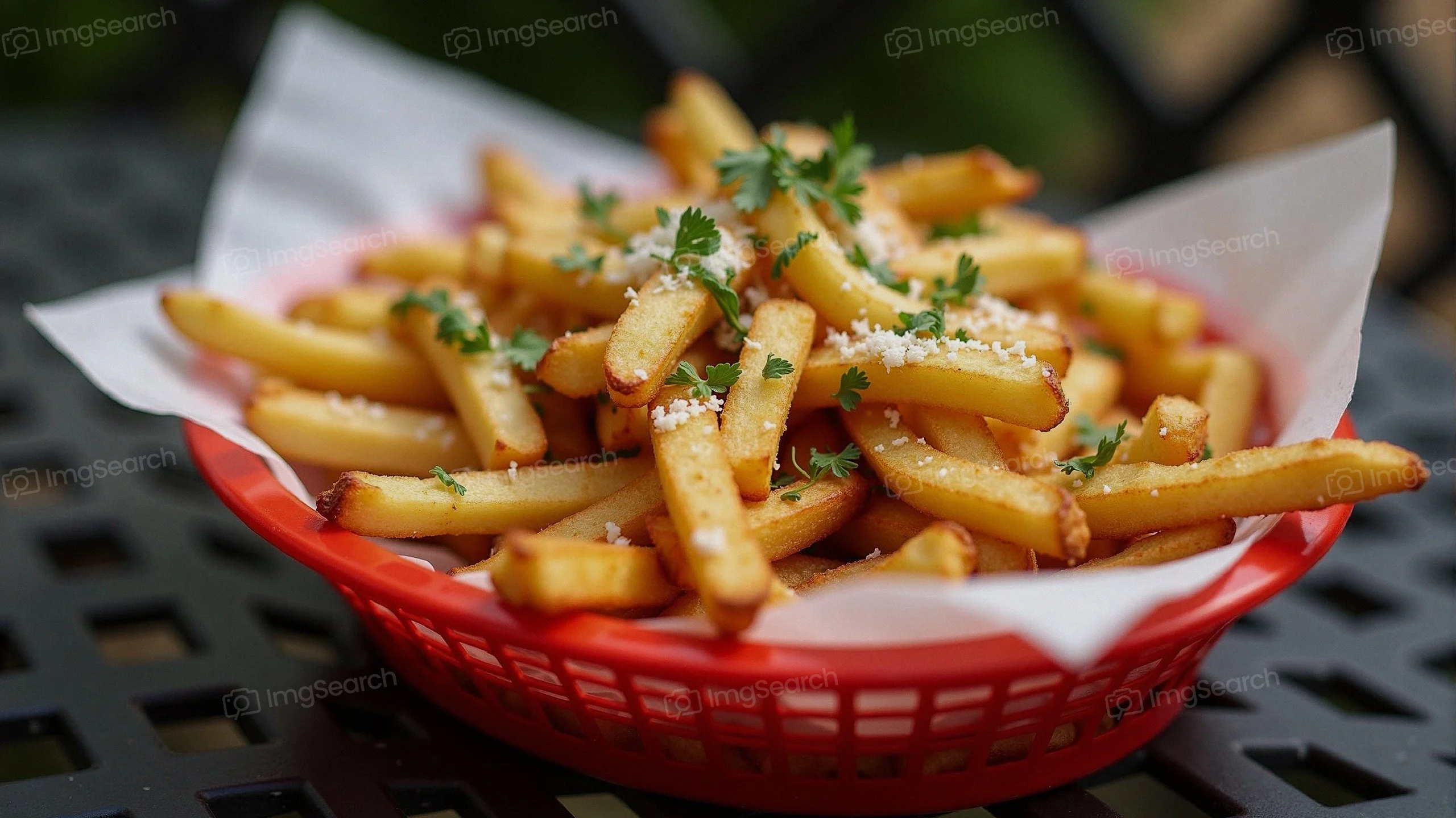 A basket of golden crispy French fries garnished with herbs cheese.