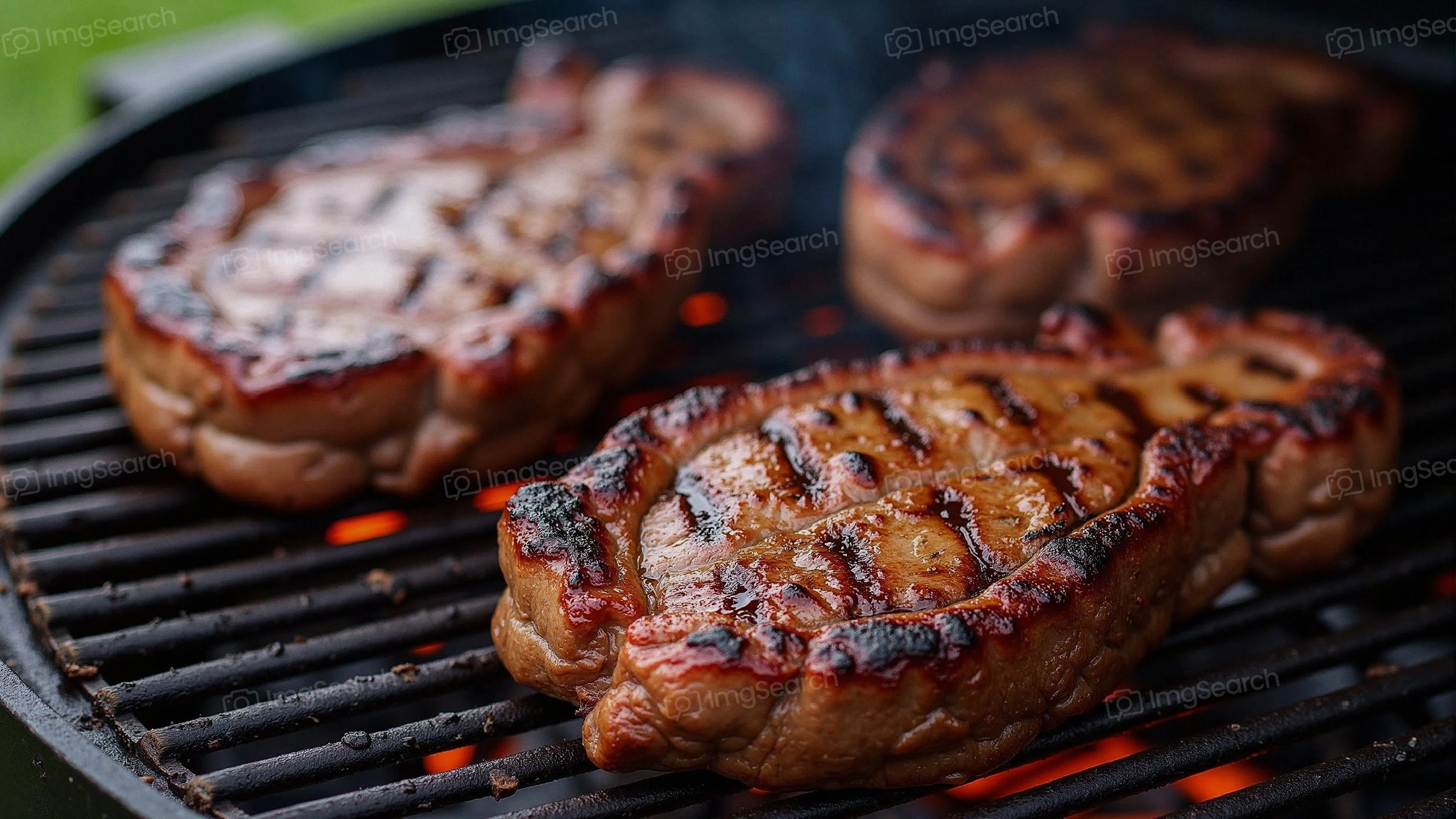 Three grilled ribeye steaks on a barbecue grill