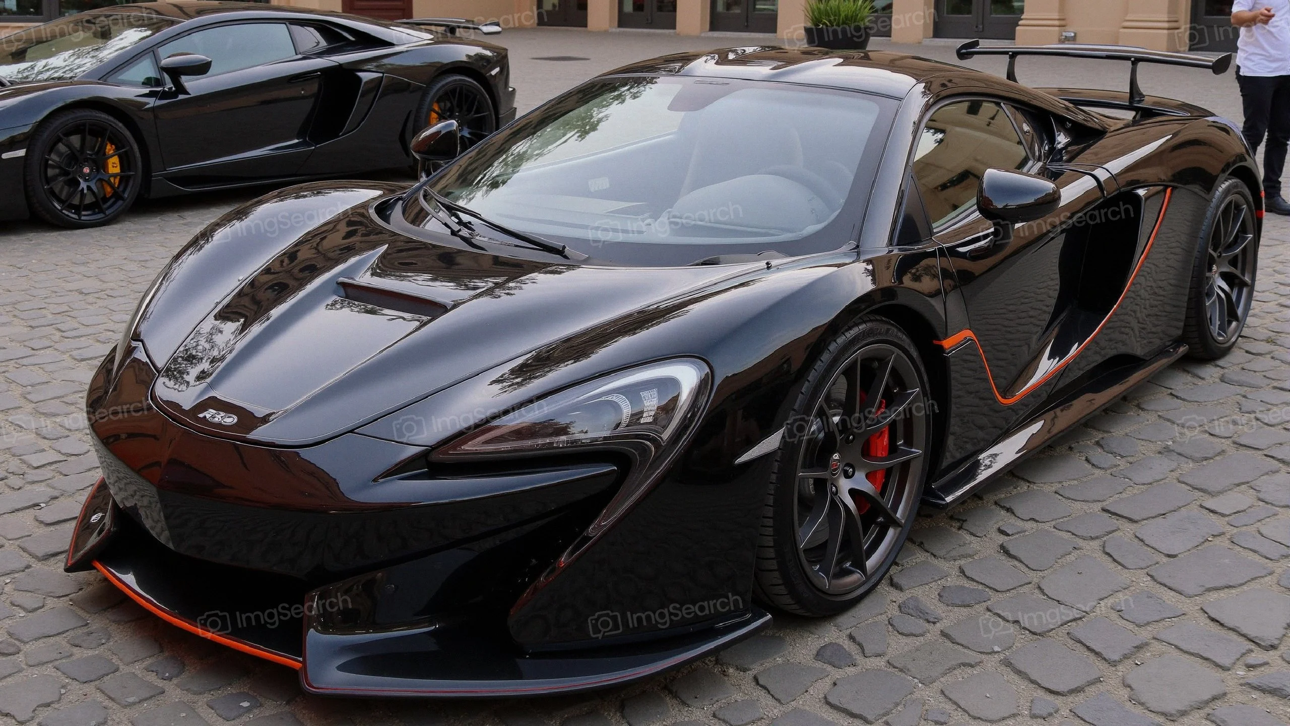 Black sports car displayed on cobblestones