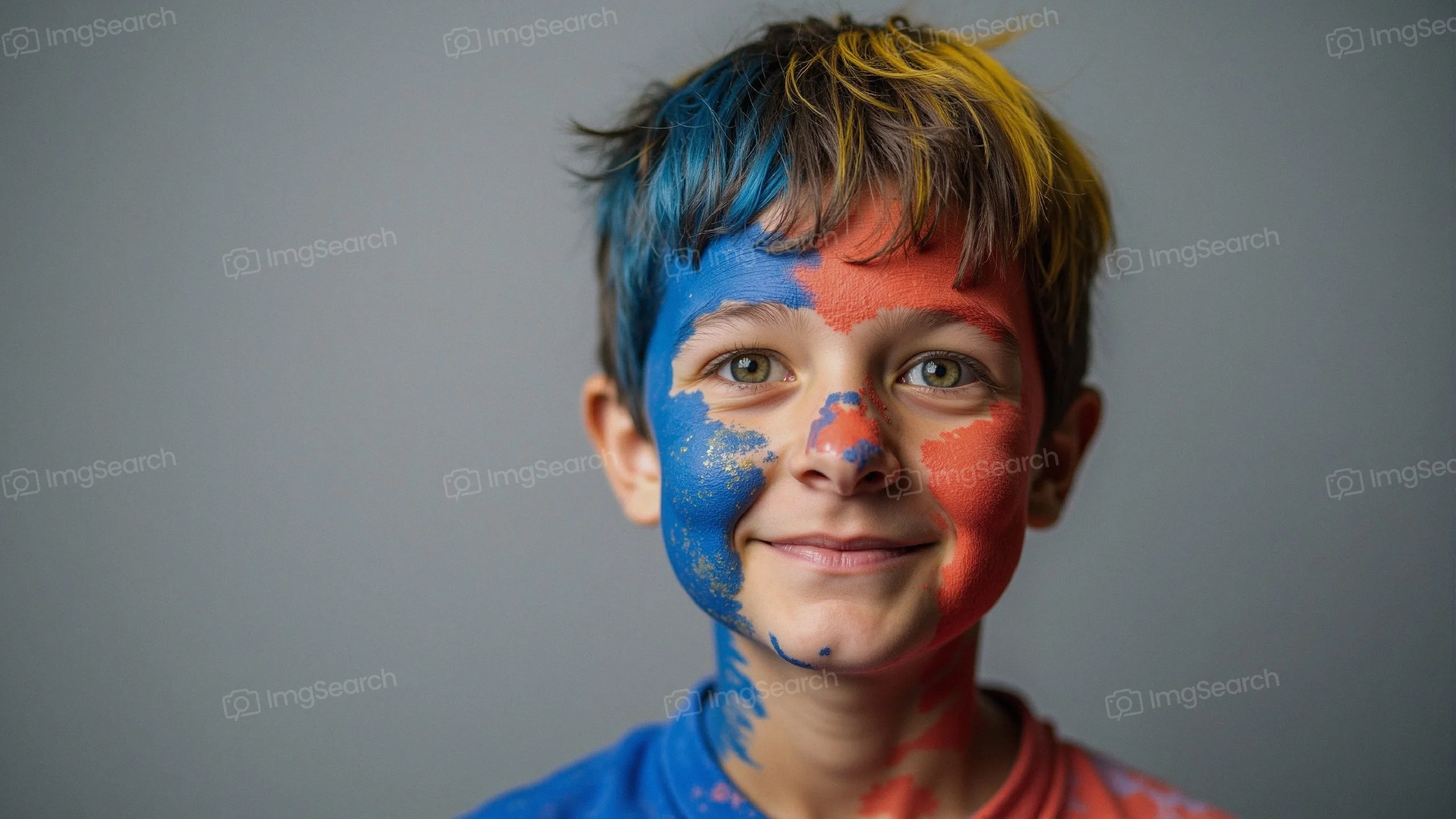 A smiley boy with blue red face paint on a gray background