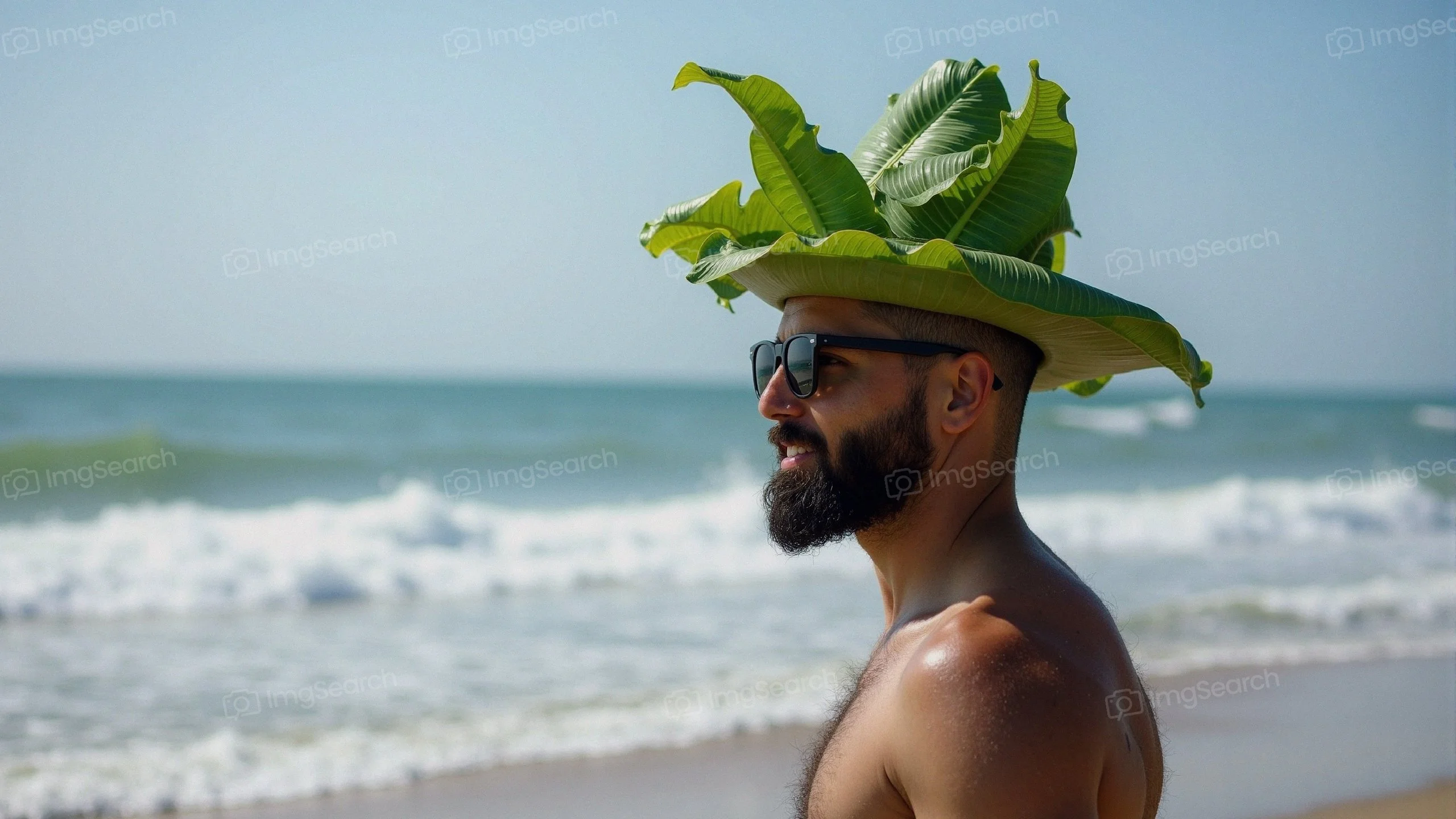 Man with a beard wearing a leaf hat and sunglasses at the beach
