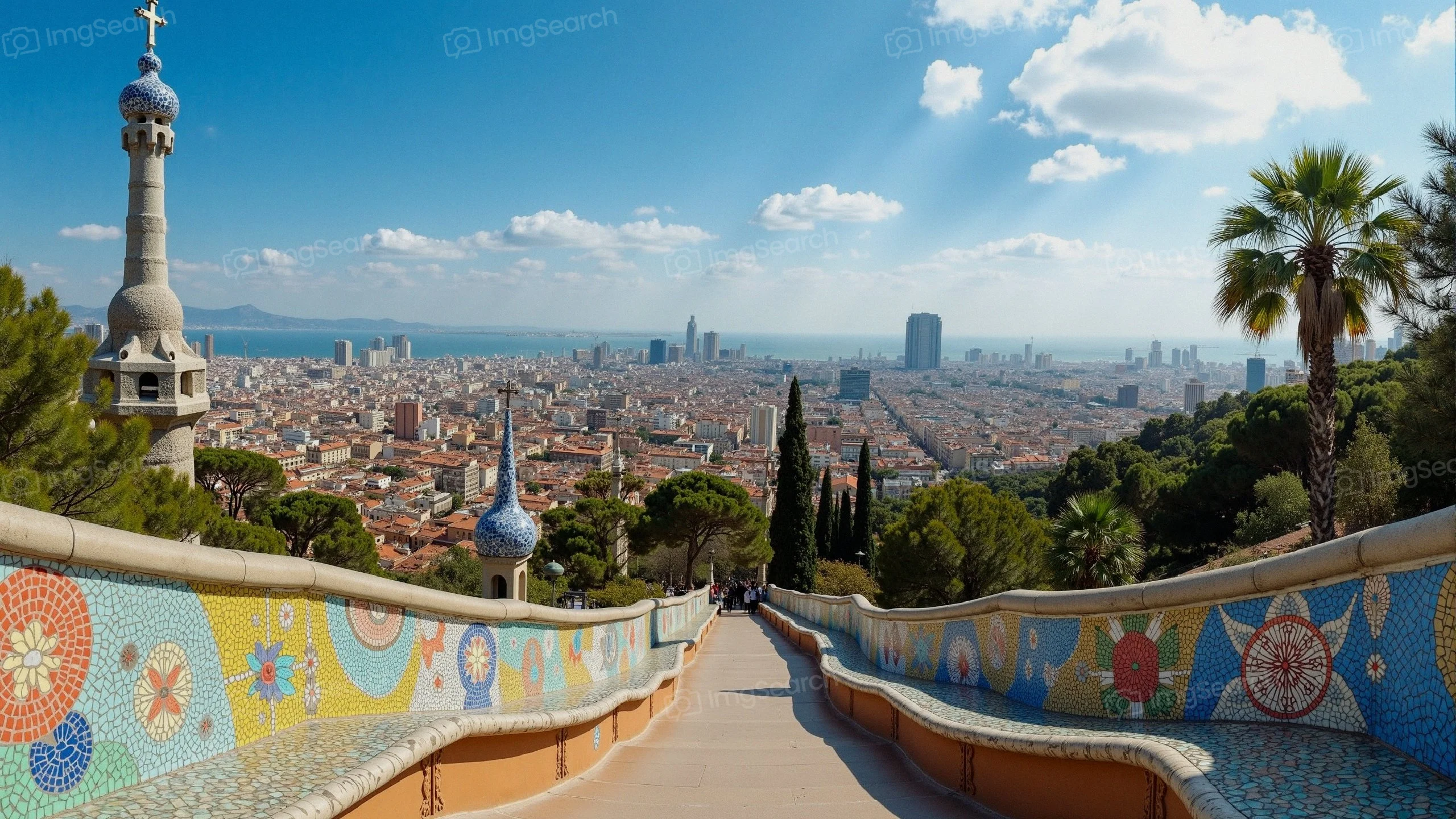 A panoramic view of Barcelona from Park Güell showcasing colorful mosaic tiles the Mediterranean Sea in the background.
