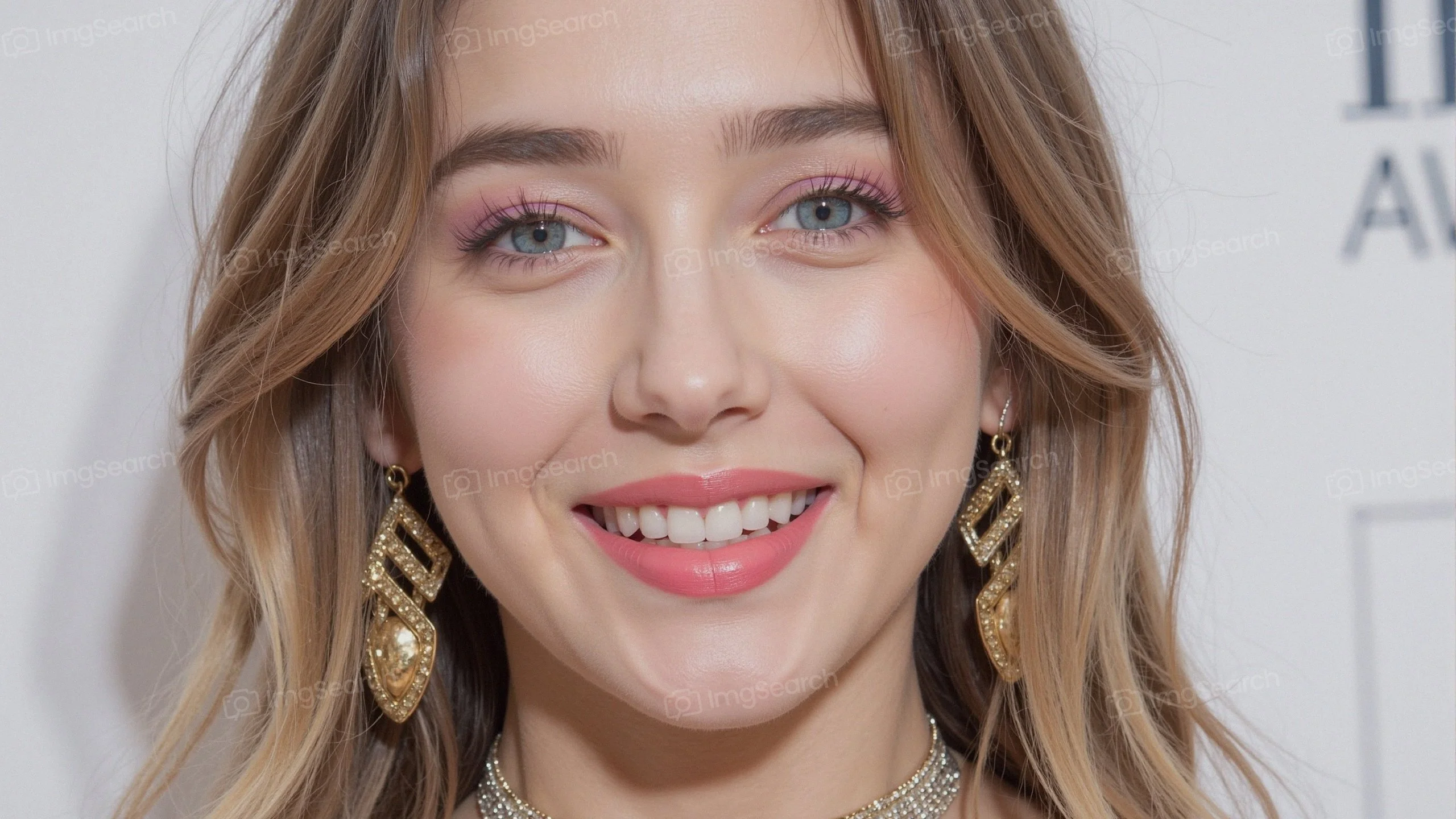 Portrait of a young woman smiling at an awards event, wearing gold earrings.