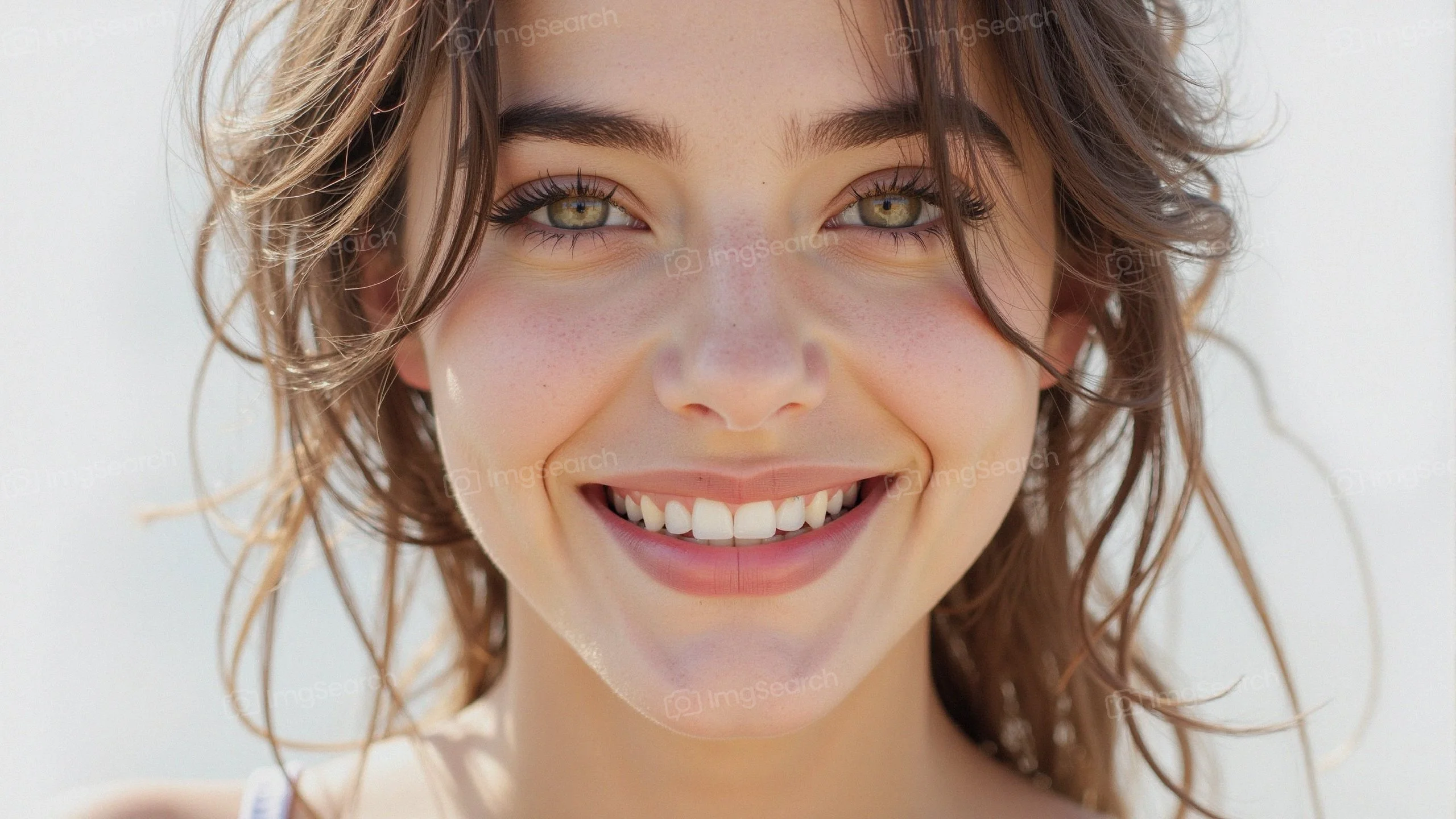 A young woman with a radiant smile, bright eyes, tousled hair in natural light.