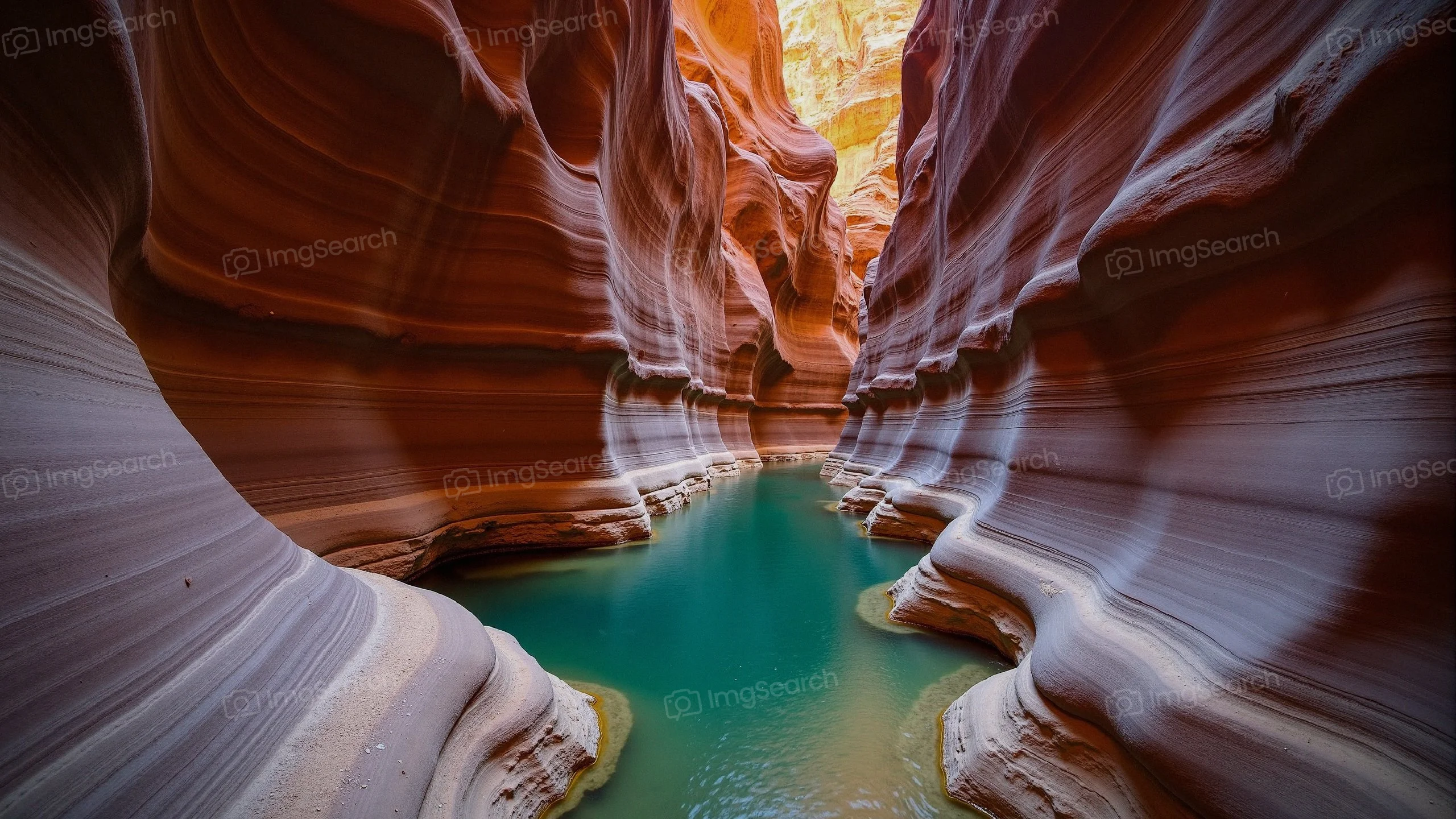 A scenic shot of Antelope Canyon with blue water surrounded by orange brown rock formations