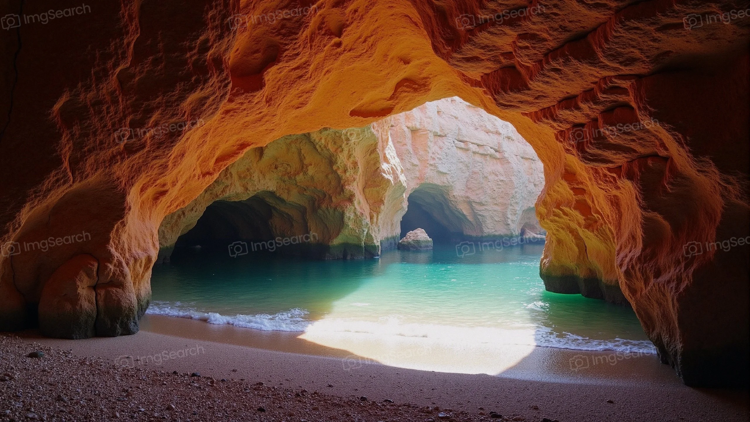 A coastal cave with turquoise waters and orange rock formations.