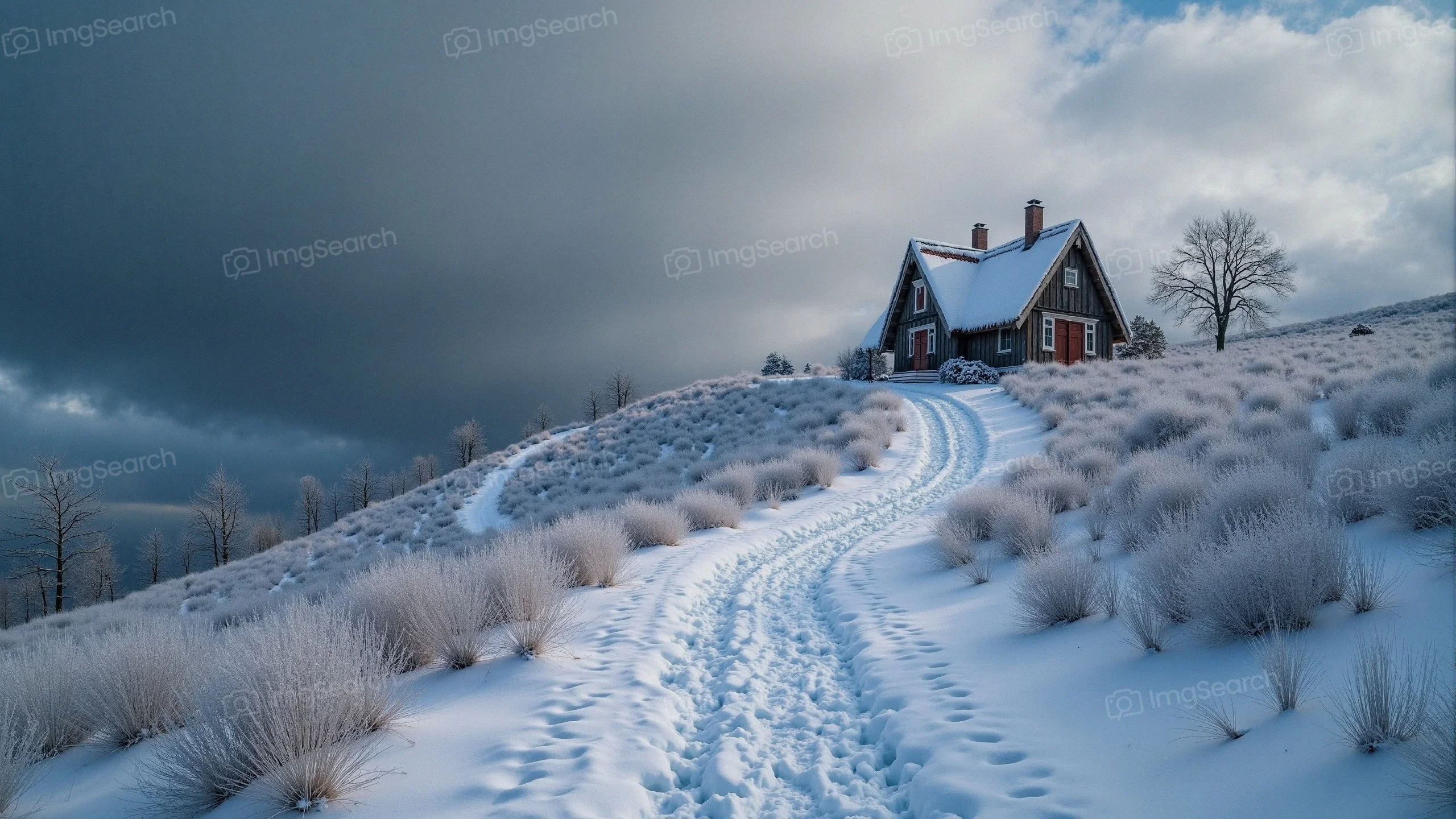 A snow-covered cabin on a hillside with a winding path under a cloudy sky.