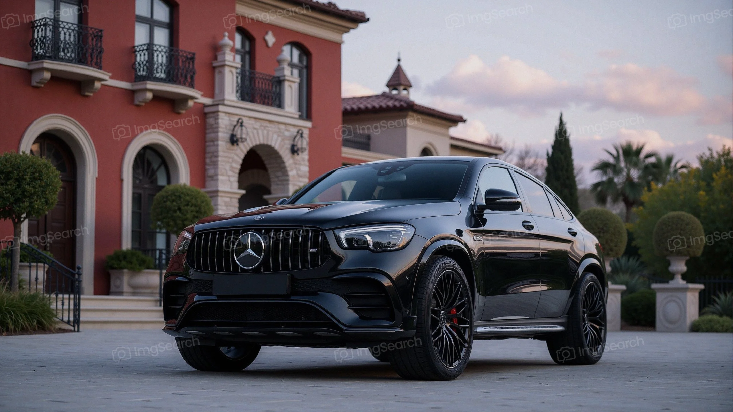 A black Mercedes-Benz SUV parked in front of an elegant villa surrounded by lush landscaping.