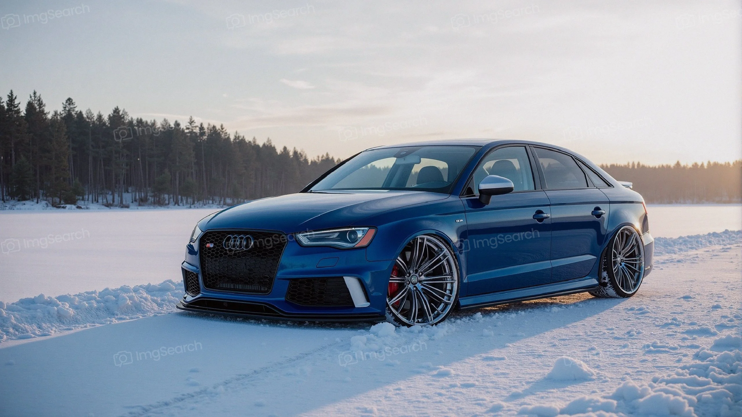 A blue Audi RS3 parked on a snowy landscape with trees in the background.