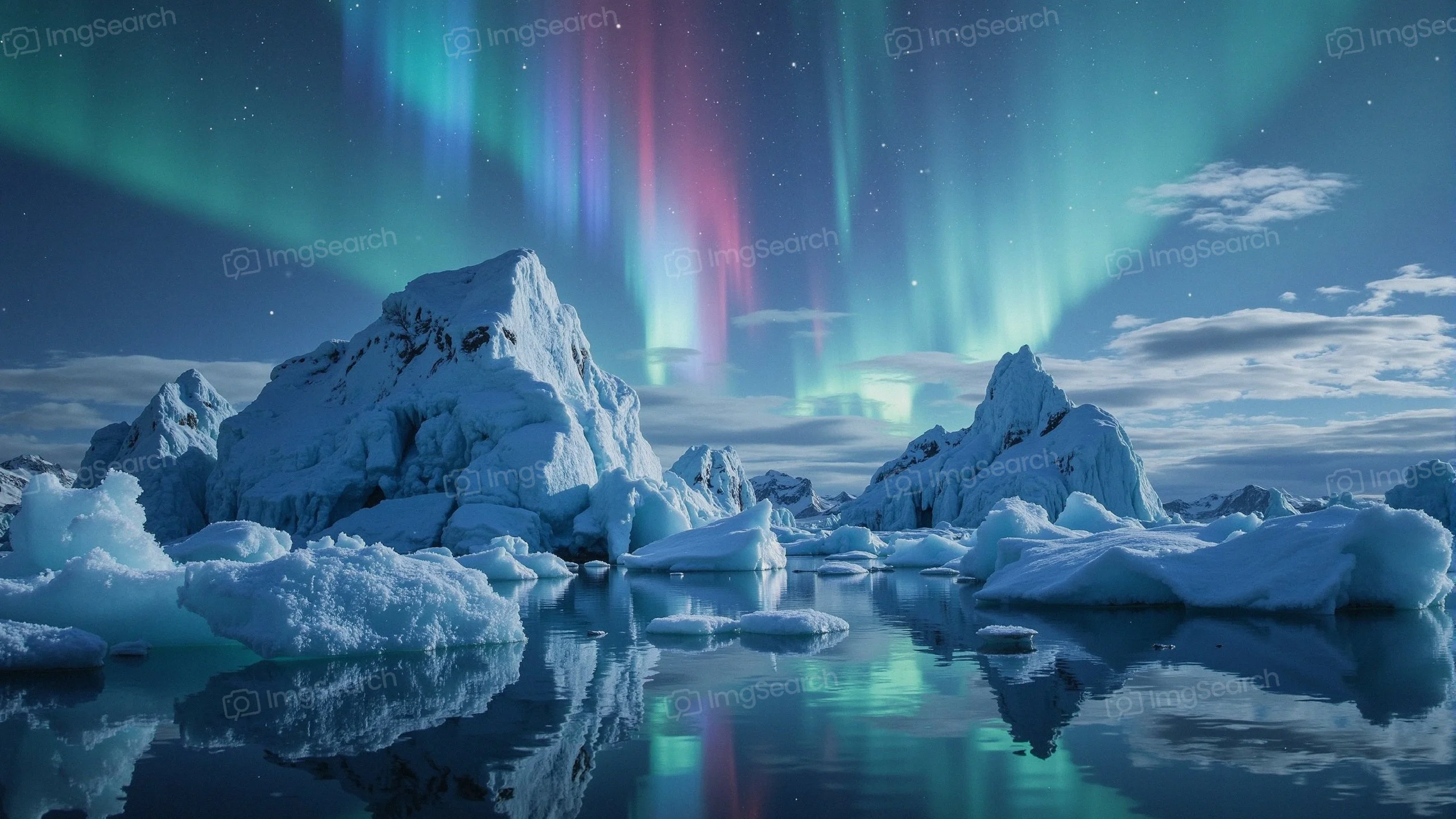 A stunning display of the Northern Lights above ice-capped mountains reflecting in a calm water body.