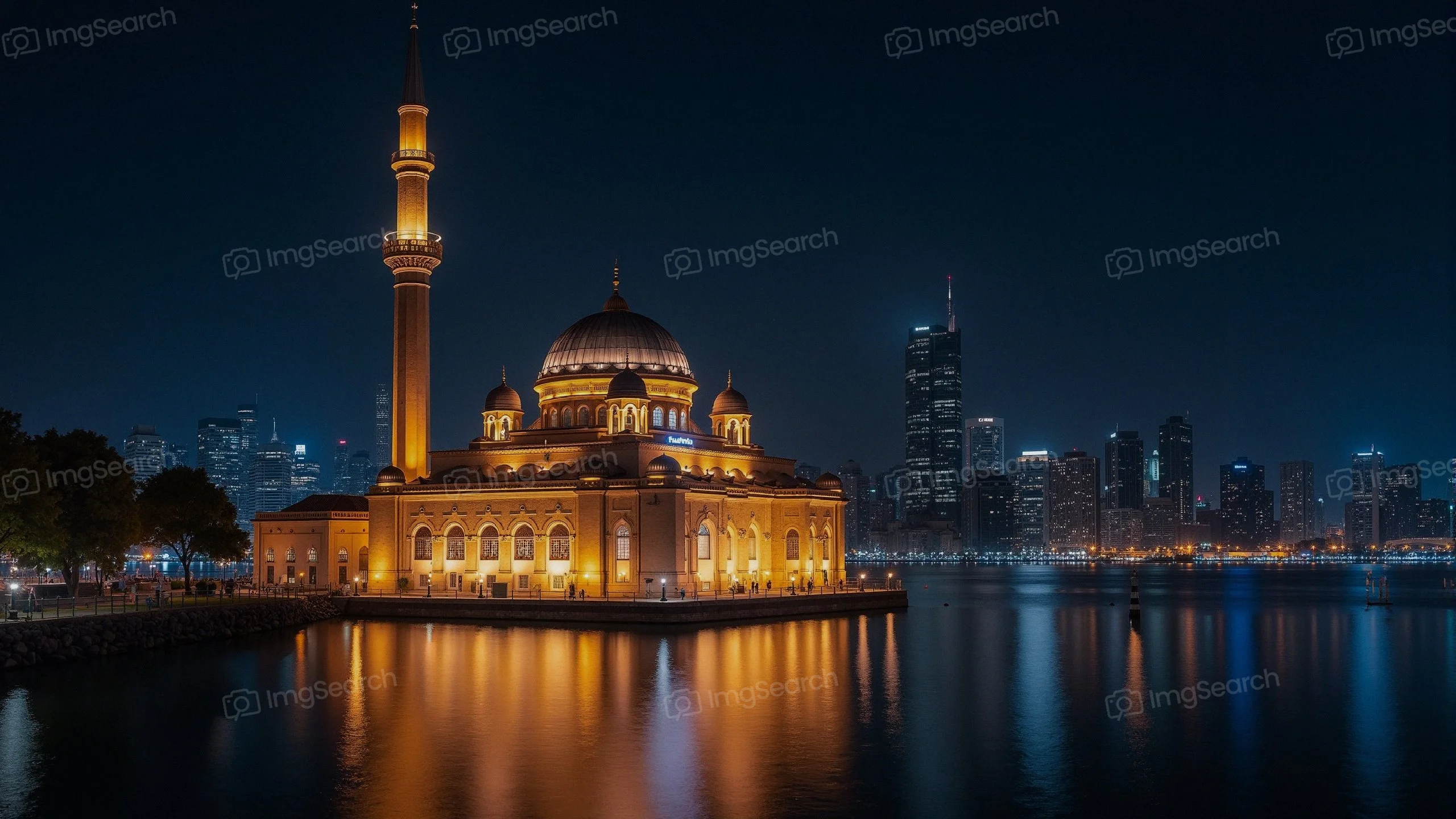 Nighttime view of a lit-up mosque with a city skyline in the background