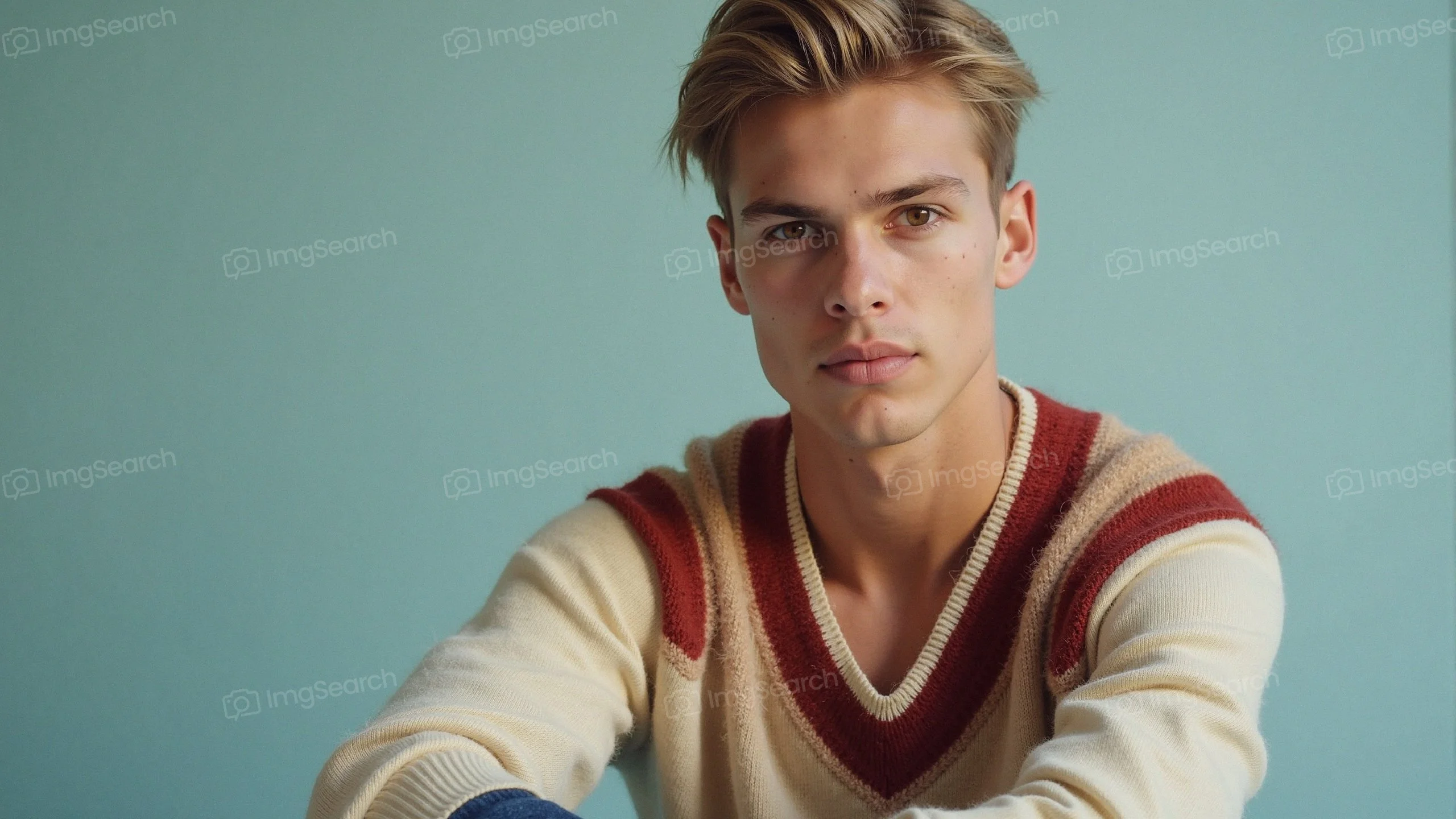 Young man in a vintage knit sweater against a teal background