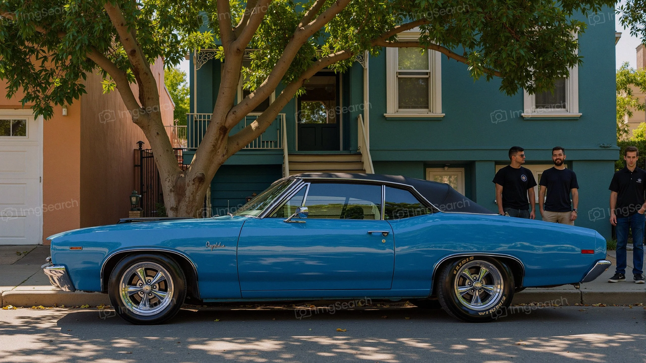 Classic blue muscle car parked under a tree with a house in the background